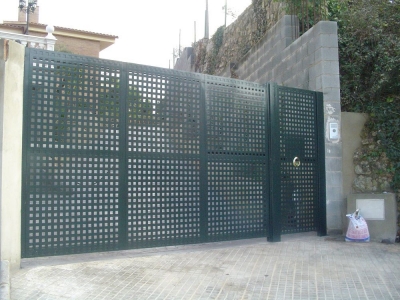 Porta cancel·la amb chapa de forat quadrat. Porta peatonal a la dreta.